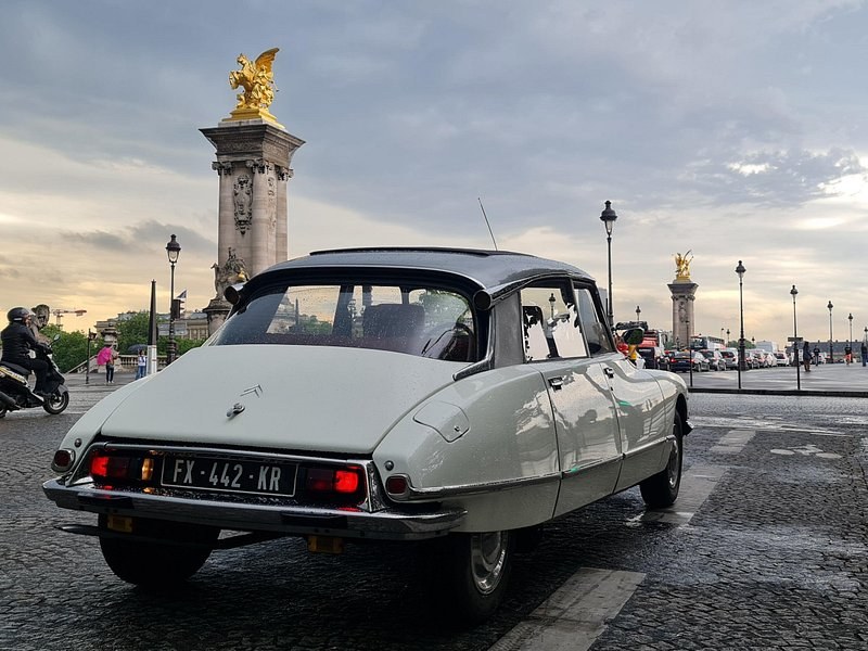 A classic car crossing the Pont Alexandre III at dusk